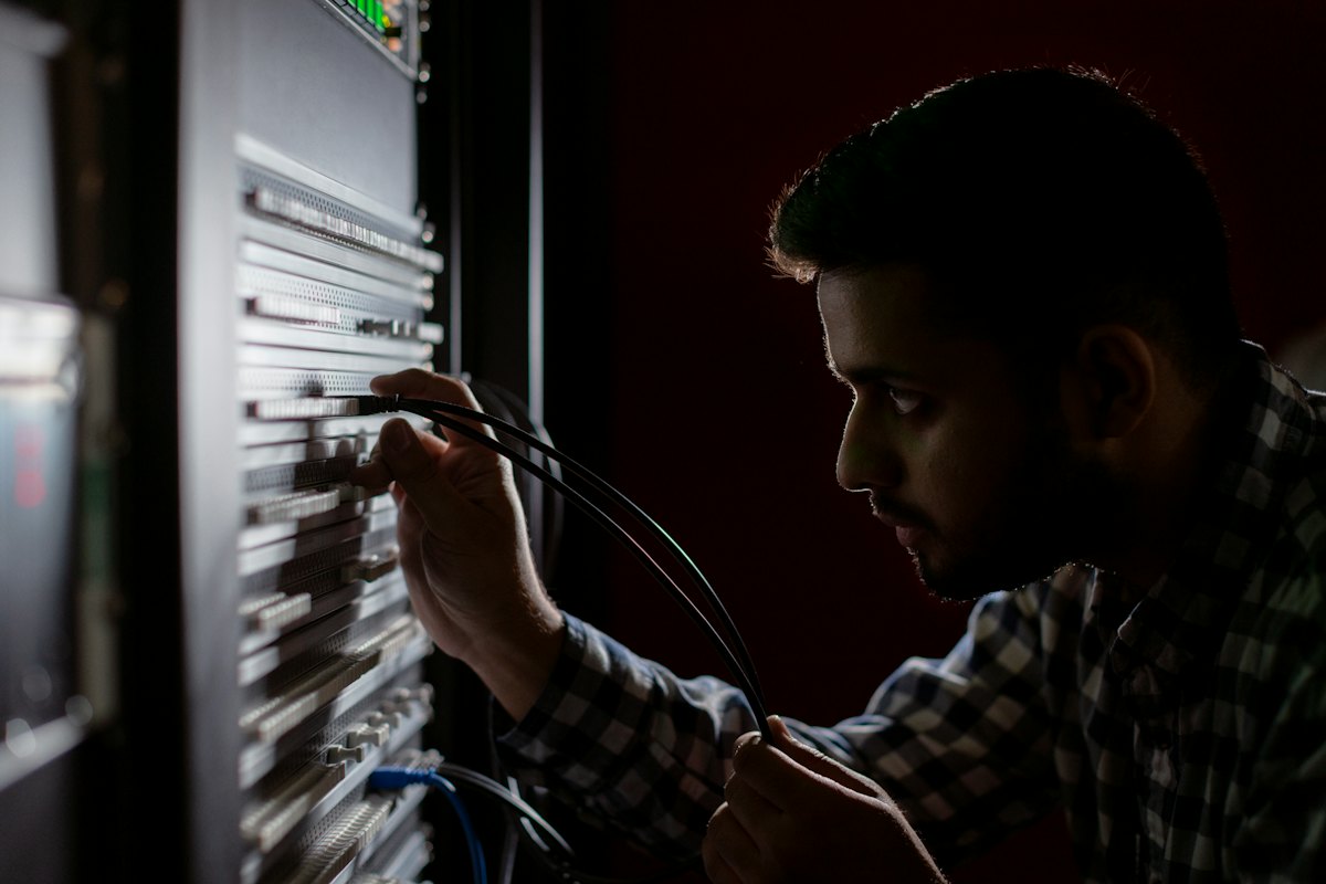 مهندس شبكات يوصل كابلات الألياف في لوحة التوزيع داخل الراك